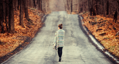 nainen kävelee yksin syksyisellä tiellä